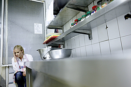 Fleischereifachverkäuferin sitzt gestresst auf dem Boden