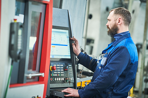 Mitarbeiter in der Produktion arbeitet an einer Maschine.
