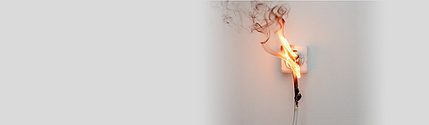 Ein Steckdose mit einem Kabel darin fängt Feuer.