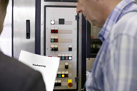 Maschinenkauf: 2 Männer mit Kaufvertrag im Betrieb vor einer Maschine