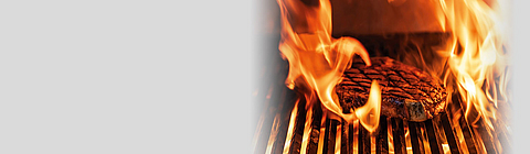 Ein Steak auf einem Grillrost zwischen Flammen