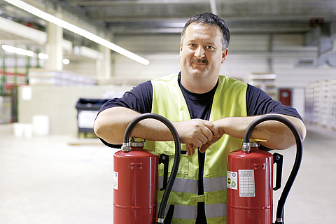 Sicherheitsfachkraft wird mit zwei Feuerlöscher in einer Lagerhalle fotografiert