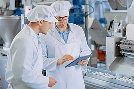 Zwei junge männliche Sicherheitsbeauftragte  kontrollieren die automatisierte Produktion in der Nahrungsmittelindustrie
