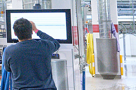 Mitarbeiter steht an einem Bildschirm in einer Abfüllhalle