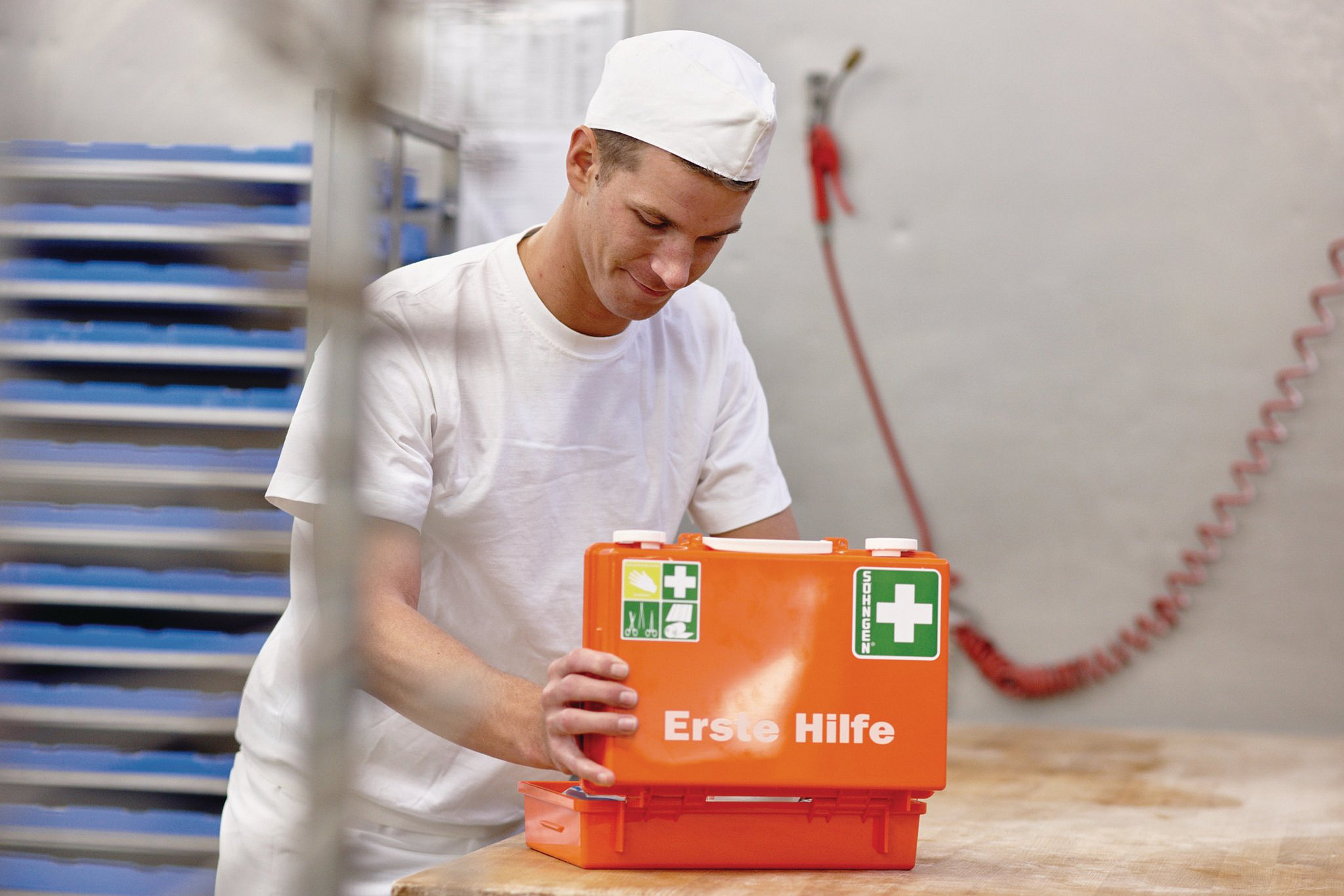 Ein junger Bäcker öffnet einen Erste-Hilfe-Kasten