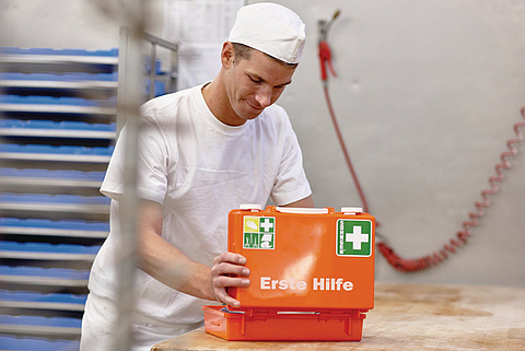 Ein junger Bäcker öffnet einen Erste-Hilfe-Kasten