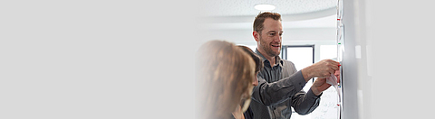 Mitarbeiter pinnt Zettel an eine Pinnwand.