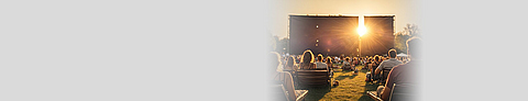 Menschen sitzen im Sommer im Open Air Kino