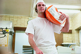 Bäcker trägt Mehlsack