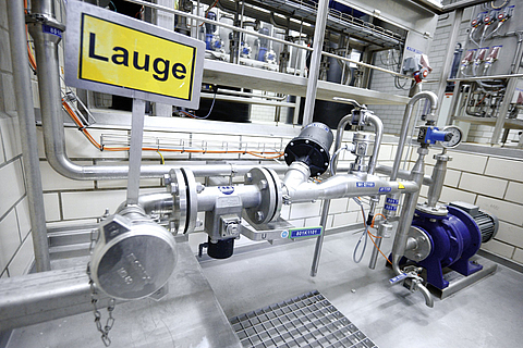 Rohrleitungssystem mit dem Hinweisschild Lauge in der Getränkeindustrie