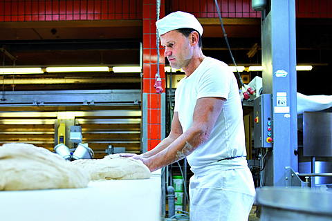 Ein Bäcker bei der Herstellung von Backwaren in einer Großbäckerei