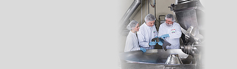 Drei Mitarbeitende stehen in Schutzkleidung vor Kutter.