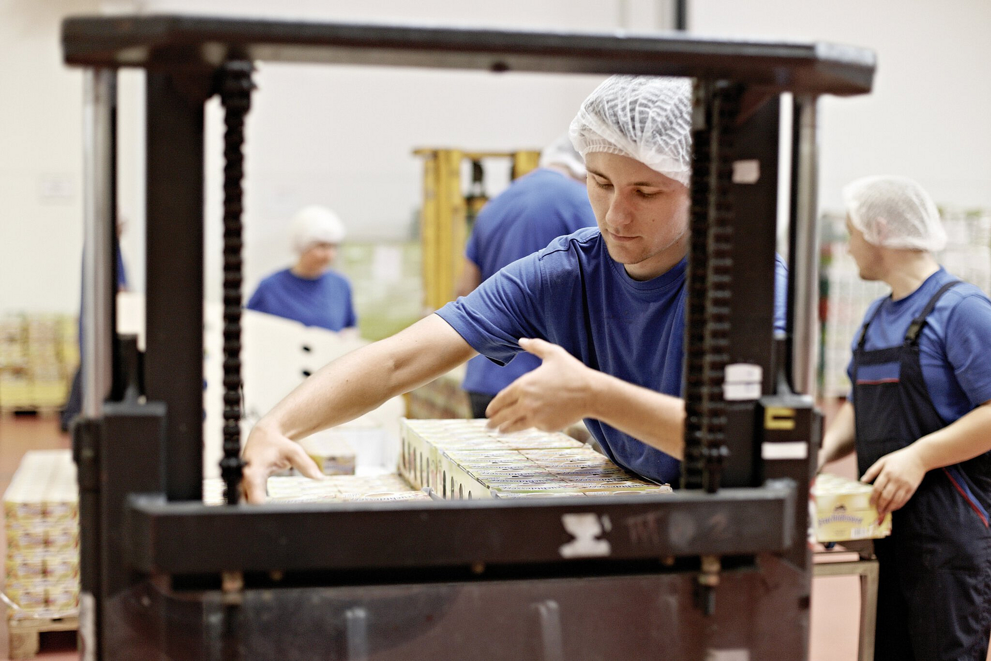 Mitarbeiter heben Kartons und setzen sie auf eine Palette