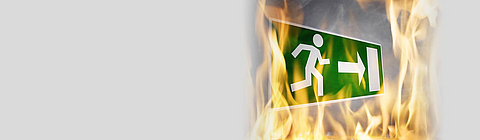Ein Hinweisschild auf Rettungswege mit Flammen darum.