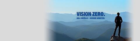 Eine Frau steht auf einem Berggipfel und schaut in die Weite.