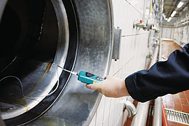 Brauereimitarbeiter misst einen Tank frei