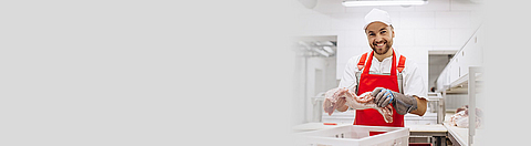 Fleischer legt bearbeitetes Stück Fleisch in eine Box