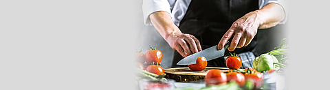 Koch schneidet Gemüse in der Küche.