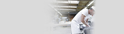 Bäcker greift in eine Knetmaschine hinein