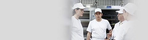 Unterweisung in Backstube: Unternehmer und drei Beschäftigte