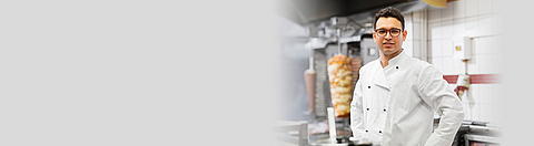 Arbeiter in Restaurant lächelt in die Kamera.