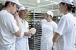 Bäckermeister führt mit drei Beschäftigten ein Unterweisungsgespräch in der Backstube
