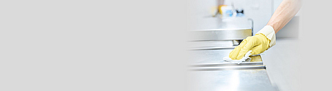 Hand mit Schutzhandschuh und Putzlappen