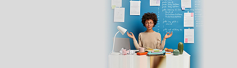 Frau am Arbeitsplatz entspannt sich mit Yoga-Pose