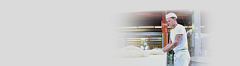 Bäcker bearbeitet Teig auf dem Backtisch