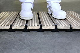 Holzrost mit  Beinen (Ausschnitt) und Arbeitsschuhen