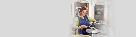 Fleischereiverkäuferin an einer Aufschnittschneidemaschine