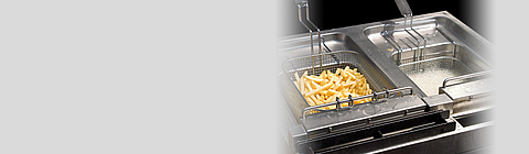 In einer Fritteuse mit zwei Körben liegen Pommes.