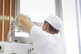 Bäcker wirft über Kopf Teigklumpen in den   Trichter eines Teigteilers                                              Trichter eines Teigteilers