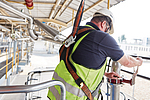 Mann ist gesichert, um in der Höhe zu arbeiten.