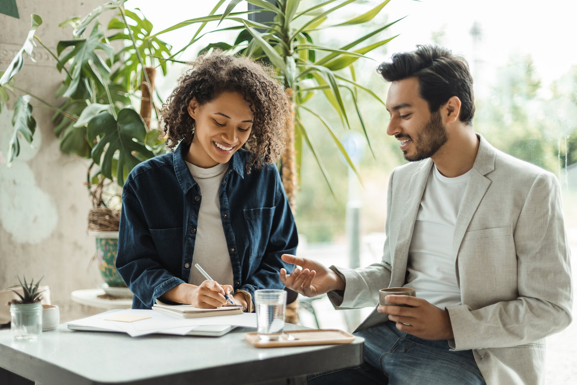 Eine Mann und eine Frau haben ein Geschäftsmeeting und machen sich Notizen.