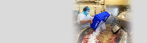 Arbeiter schüttet Salz in laufenden Fleischkutter.