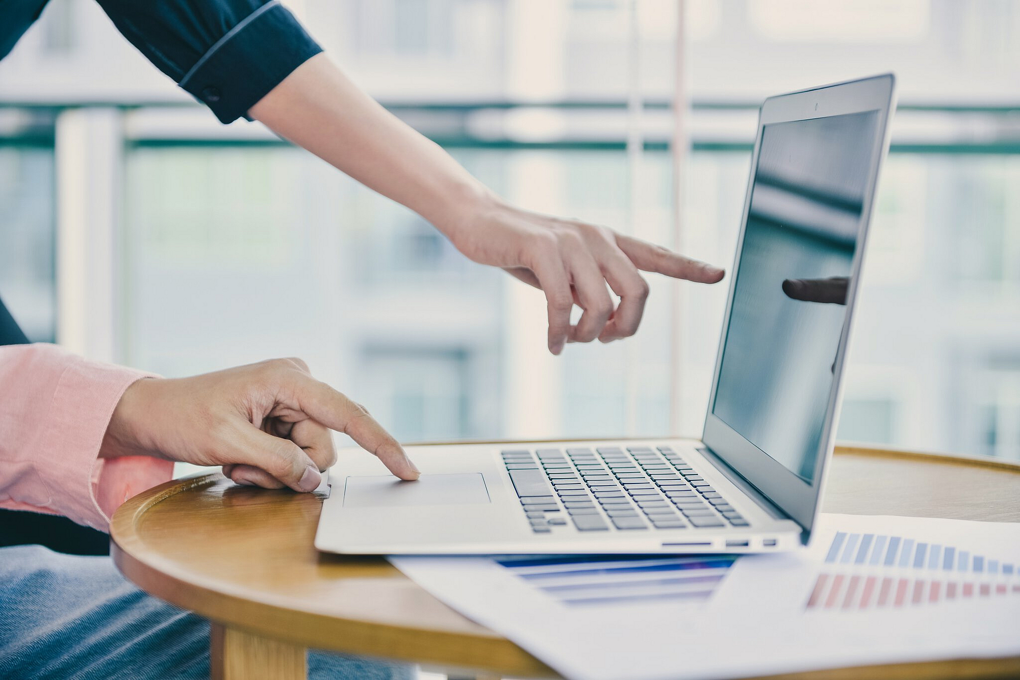 Weibliche Hand zeigt mit Finger auf Bildschirm eines Laptops