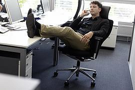 Mitarbeiter im Büro telefoniert und hat die Beine auf den Schreibtisch gelegt