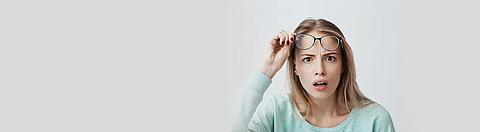 Eine Frau reißt vor Erstaunen die Augen auf und zieht ihre Brille ab. | © Cookie Studio 2017 - stock.adobe.com Eine Frau reißt vor Erstaunen die Augen auf und zieht ihre Brille ab.