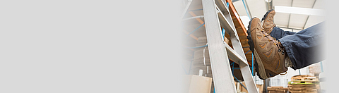 Mensch fällt von der Leiter beim Arbeiten in einem Lagerraum