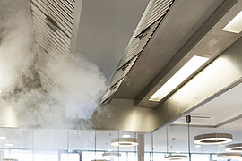 Küchenlüftung: Koch steht am Herd, Wasserdampf zieht aus Topf nach oben