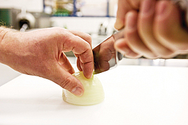 Eine Zwiebel wird mit dem "Krallengriff" geschnitten.