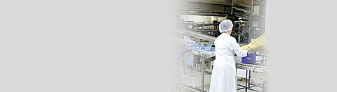 Mitarbeiterin an einem höhenverstellbaren Arbeitstisch faltet Kartons in der Verpackung auf