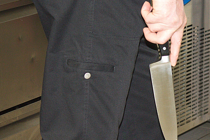 Messer wird von Koch mit der Spitze nach unten getragen