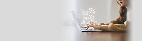 Frau nutzt Laptop und versendet Online-Nachrichten mit E-Mail-Symbol