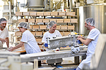 Fröhliche Arbeiter bei der Herstellung von Backwaren und Broten in einer Großbäckerei