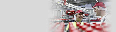 Mitarbeiterin und Mitarbeiter in Abfüllhalle im Gespräch