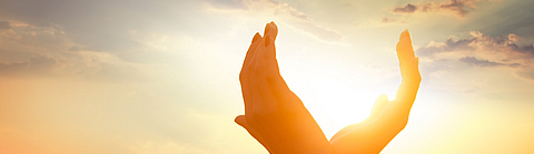 Hände halten die Sonne im Morgengrauen