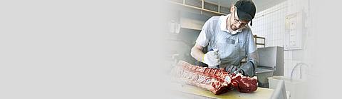 Fleischer mit PSA bearbeitet Fleisch mit Messer