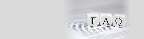 Drei Würfel auf einem bedruckten Papier zeigen jeweils F, A und Q.